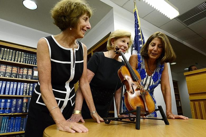 Sisters (from left) Jill, Nina and Amy Totenberg with the Ames Stradivarius violin at a press conference at a New York Justice Department office on Thursday. The violin was stolen in 1980 from their father.