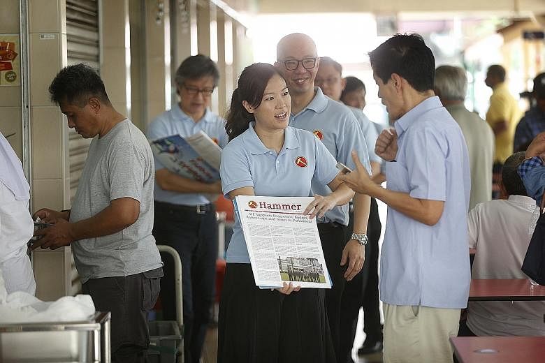 Potential Workers' Party candidates He Ting Ru (centre, front) and Terence Tan (behind her) on a "Hammer outreach" - selling the WP newsletter, the Hammer - during a walkabout at the Haig Road food centre yesterday.