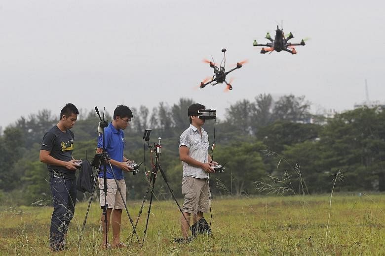 Drone racers (from left) Xu Zhuohua, Wong Wen Jie and Garry Huang get their speed fix in an open field and can view the landscape from their drones' perspective on a mounted monitor (below).