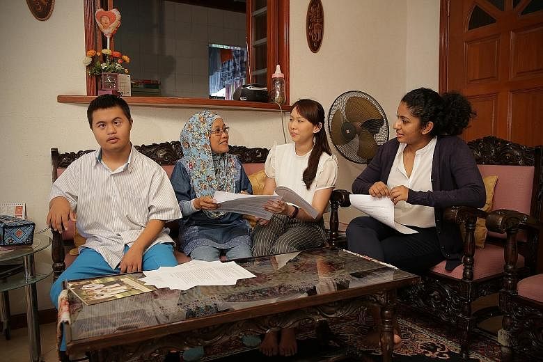 Helping Madam Halela Mawardi (second from left) with the application forms for a deputyship order to manage the affairs of her teenage son Muhammad Muhyiddin (far left) when he turns 21 are law undergraduates Kerri Tan and Mehaerun Simaa.