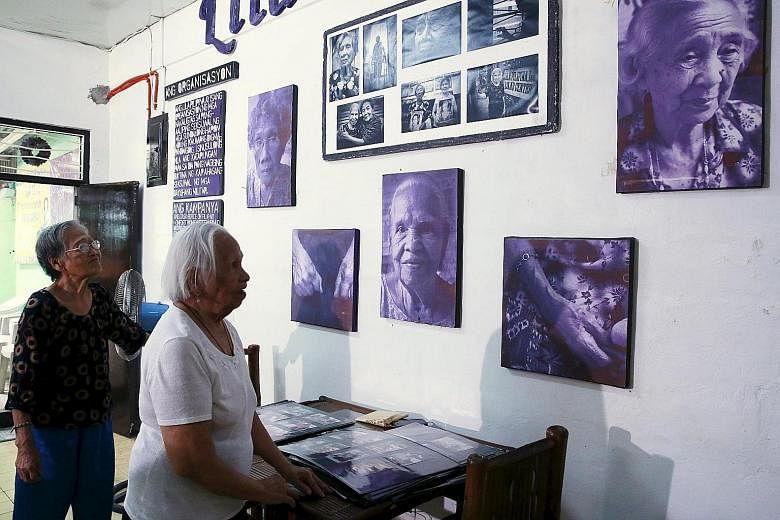 Ms Estelita Dy (left) and Ms Hilaria Bustamante, who were "comfort women" during World War II, looking at pictures of fellow survivors at a resource centre run by women's rights group Lila Pilipina in Quezon city, Manila, yesterday. The Filipino wome