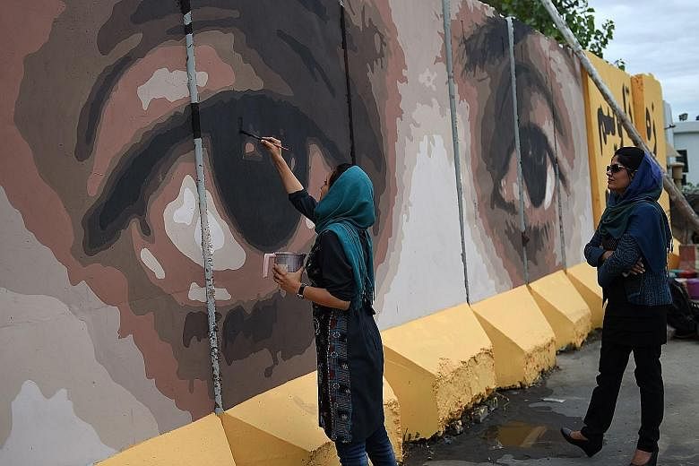 Afghan artists and volunteers painting the eyes of a woman on a barrier wall at the presidential palace in Kabul on July 21. Alongside the eyes, a slogan reads: "Corruption cannot be hidden from God or from the people."