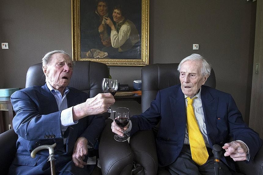 The world's oldest living twin brothers, Paulus (left) and Pieter Langerock, aged 102, toasting at the Ter Venne care home in Sint- Martens-Latem, Belgium, yesterday. Born on July 8, 1913, the Belgians never married and until this day, sleep side by 
