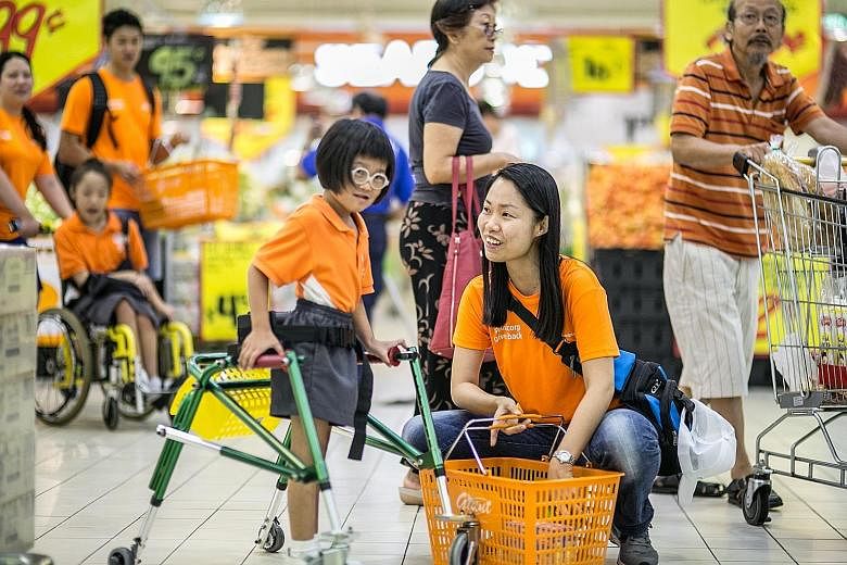 Seven-year-old Nur Andreanna Ashmoori, a pupil from the Cerebral Palsy Alliance Singapore School, got her own "shopping assistant" at a supermarket yesterday. Ms Wendy Khoo, 40, assistant health safety and environment manager at Sembcorp Utilities Si