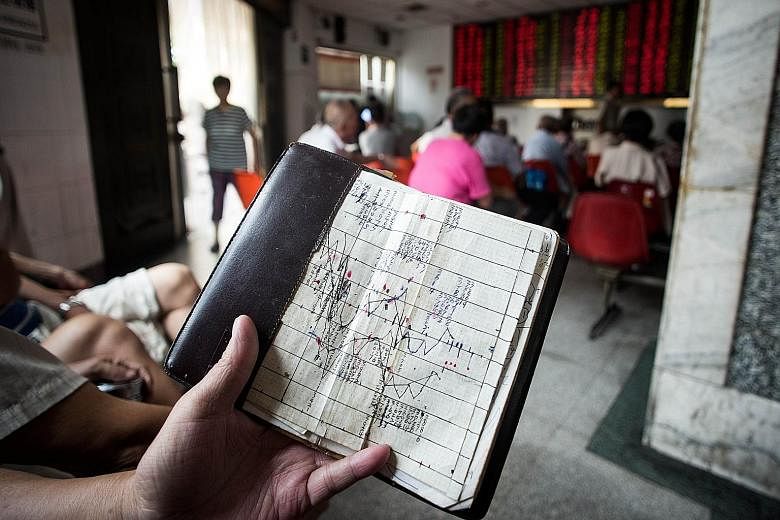 An investor studying a notebook showing stock market movements at a brokerage house in Shanghai yesterday. China's move to devalue the yuan for the third day in a row sent jitters worldwide.