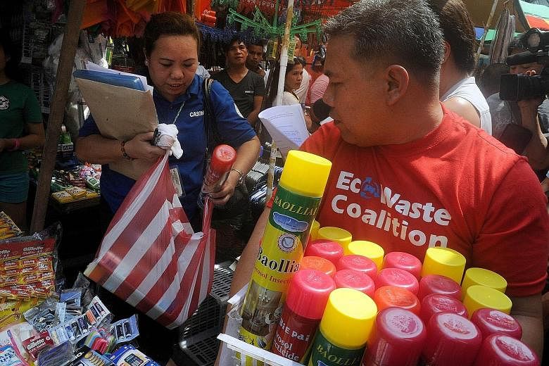 A sanitation officer (left) from the Manila Health Department (MHD) and an EcoWaste Coalition member confiscating unregistered household insecticides for sale at a shop in Manila yesterday. Members of the MHD conducted the search after claims by chem