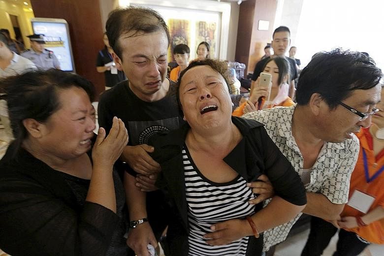 The mother of a missing firefighter being helped by family members as they wept outside the venue of a news conference in Tianjin.