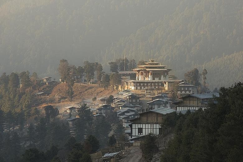 Bhutan's monasteries, such as this one on the left, have not been overrun by mass tourism. The 400-year-old multi-tiered Gangtey Goenpa monastery (above) stands on a ridge. Balloon pilot Cary Crawley (above, centre) with Mr Brett Melzer and his wife 