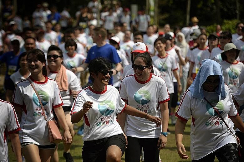 Staff from the National Healthcare Group at a community walk at MacRitchie Reservoir yesterday. Around 500 people from NHG participated, along with 10 patients from IMH and staff from the Dover Park Hospice.