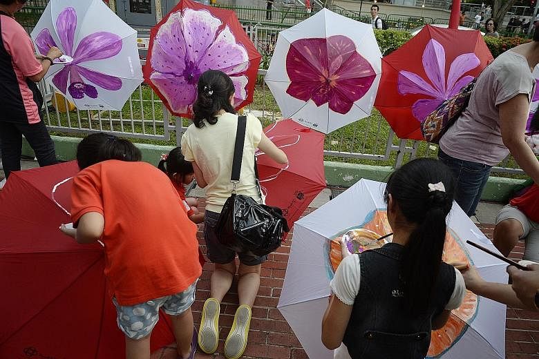 Marine Parade residents painting on umbrellas at the PAssionArts Festival held at Marine Parade Promenade yesterday. The PAssionArts Village @ Arts D'Marquee celebrated the heritage of the nearby Joo Chiat and Katong areas and welcomed crowds of abou
