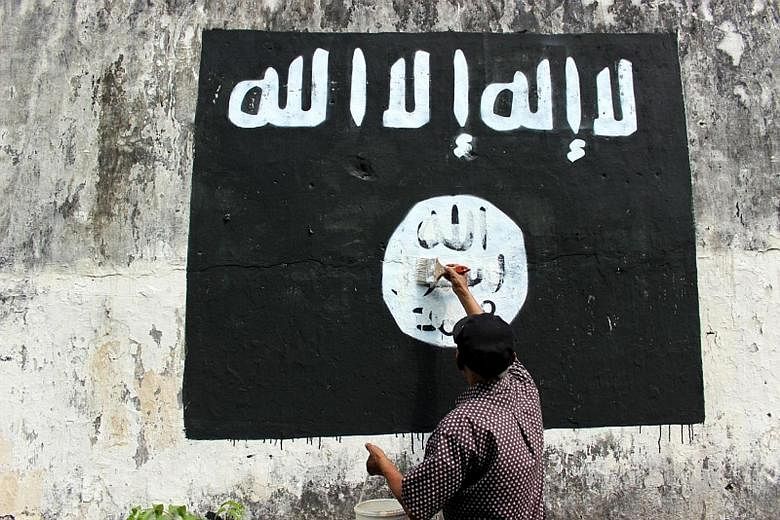 A resident of Solo, in central Java, painting over an ISIS flag.