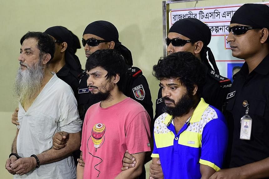 Security personnel with suspects (from left) Touhidur Rahman, Sadek Ali and Aminul Mollick at a media briefing in Dhaka yesterday. Police say Rahman, a British citizen, was the main planner of the killings.