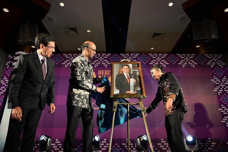 DPM Tharman Shanmugaratnam (centre) and Mr Mohd Saat Abdul Rahman (right), editor of Malay daily Berita Harian, unveiling a portrait of Mr Mohammad Alami Musa (left), this year's Berita Harian Achiever of the Year, at the award ceremony last night.
