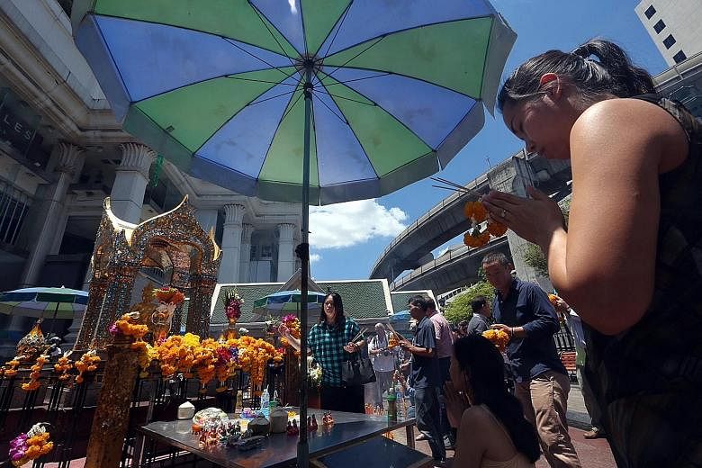 Visitors praying at Erawan Shrine in Bangkok after it reopened yesterday morning, less than 48 hours after the bomb attack on Monday night. A constant stream of people turned up yesterday to offer flowers and notes in memory of the victims. The Thai 