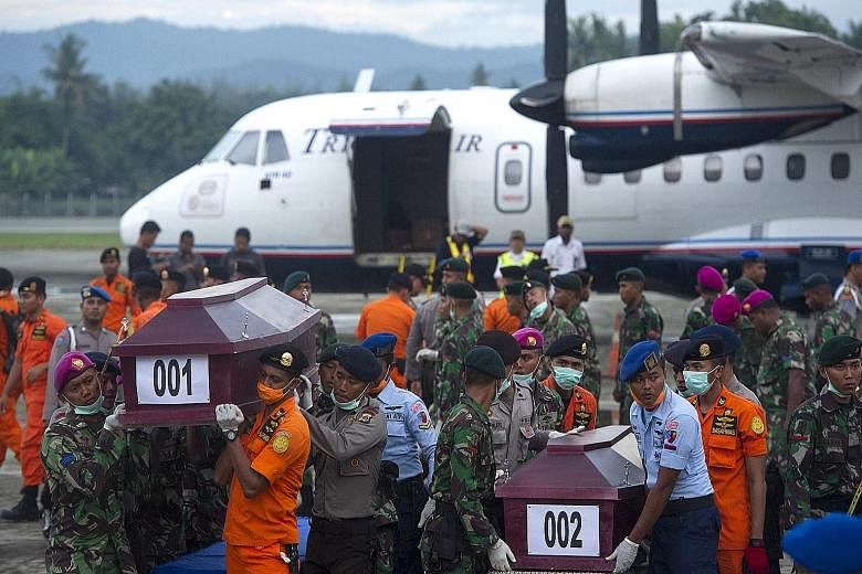 Indonesian security forces and rescue teams carrying coffins containing the remains of some of the passengers recovered from the crash site of the Trigana Air plane yesterday at Sentani Airport, near Jayapura, Papua province.