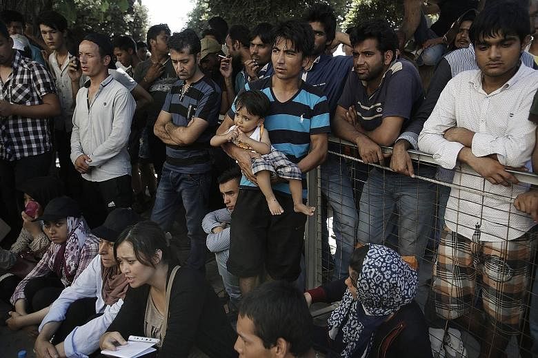 Pakistani and Afghan migrants awaiting registration outside a police station on the Greek island of Kos yesterday. Some 250,000 migrants have already crossed the Mediterranean this year to Italy and Greece. The number is expected to pass 300,000 by e