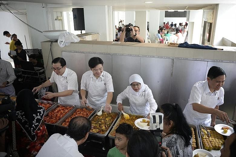PAP candidates in Marsiling-Yew Tee GRC (from left) Ong Teng Koon, Lawrence Wong, Halimah Yacob and Alex Yam dishing out servings of fried rice, beehoon, sayur lodeh, chicken wings and siew mai to residents, many of them pioneers, at a block of renta