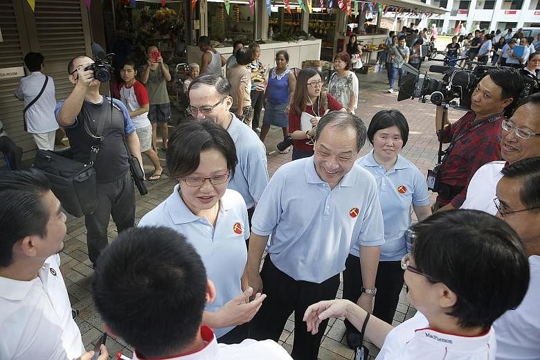 Workers' Party leaders Sylvia Lim (third from left) and Low Thia Khiang greeting People's Action Party members during a walkabout at MacPherson Market and Food Centre on Aug 7.