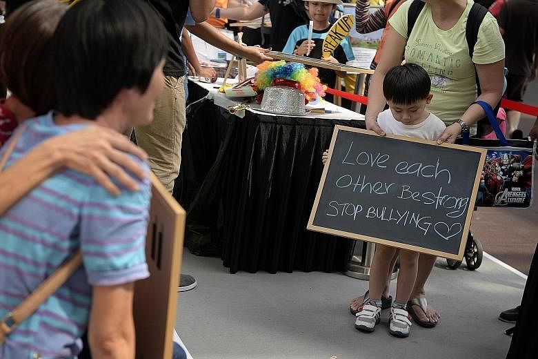 Six-year-old Max Wan doing his bit to spread the anti-bullying message at the Singapore Children's Society roadshow yesterday. With him is his mother Katherine Lim, 41.