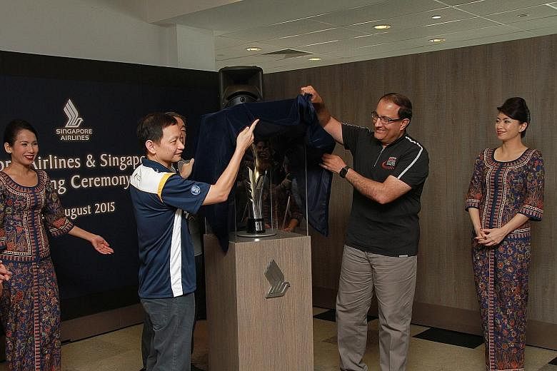SIA chief executive Goh Choon Phong (left) and Second Minister for Trade and Industry S. Iswaran unveil this year's Formula One Singapore Grand Prix trophy.