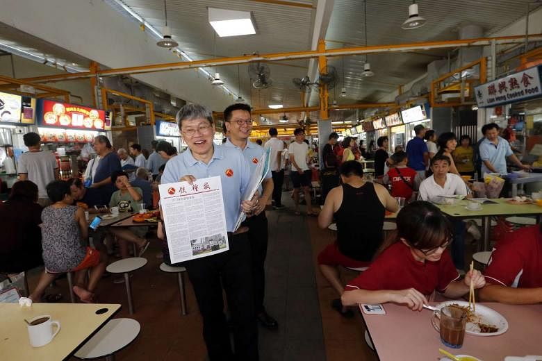 Mr Png Eng Huat (holding sign) and Mr Daniel Goh of the Workers' Party at the Fengshan hawker centre earlier this month.