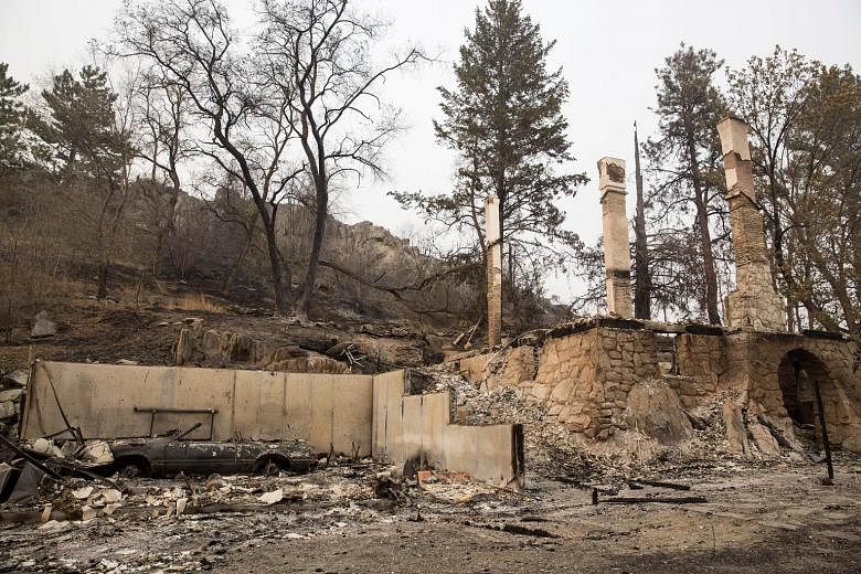 A charred car sits amid the ruins of a house destroyed by wildfires on Saturday near Okanogan, Washington. A series of blazes called the Okanogan Complex, which is made up of five wildfires in north-central Washington state, has scorched 65,154ha of 