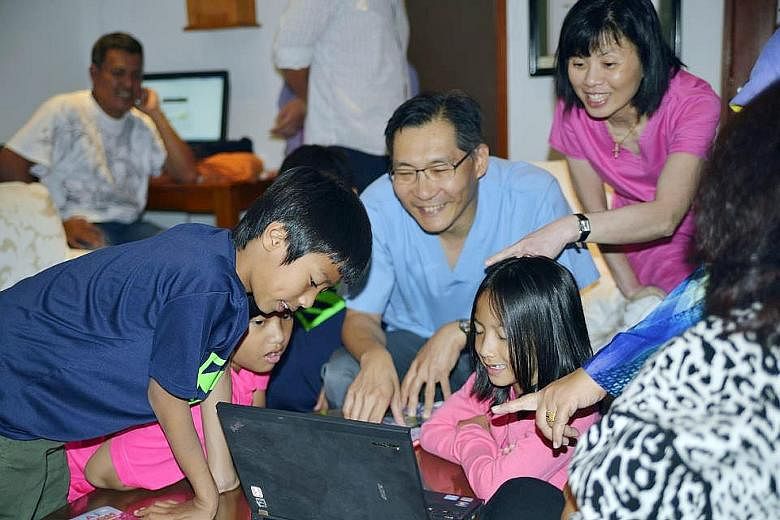 (Above, from left) Indonesian triplets Aisya Anjani, Aditya Harimurti and Artha Pradipta, nine, with younger sister Adinda Rania, seven. (Left) The children looking at family photos with Dr Cheng Li Chang (in blue shirt) and one of the nurses who att