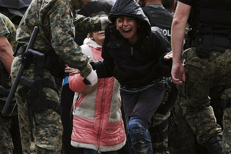 A migrant girl crying in relief after crossing Greece into Macedonia near Gevgelija last Saturday. After a futile attempt to slow down the flow of migrants, Macedonia laid on extra trains and buses to help ferry the migrants to Serbia instead.