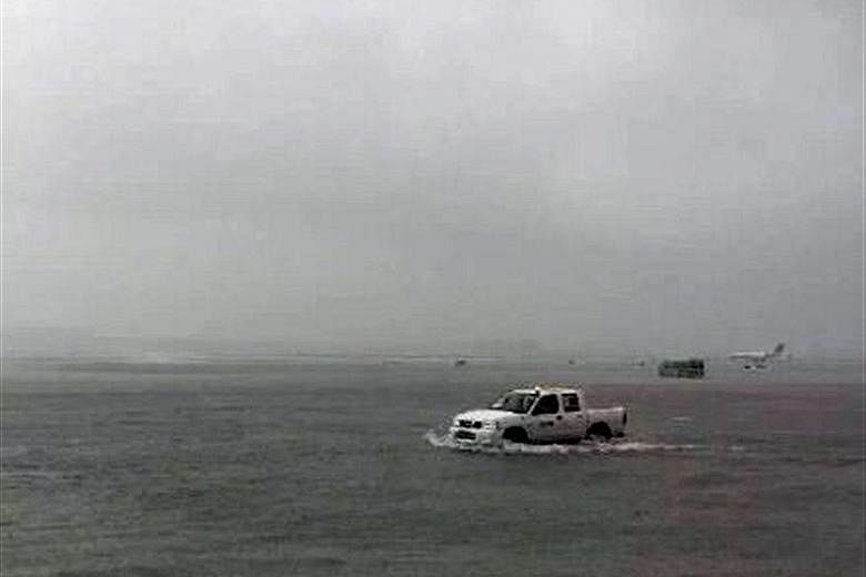 An airport vehicle making its way across a flooded runway at Hongqiao International Airport (above), while people try to stay dry (left) in flooded areas of Shanghai after the combined effect of Typhoon Goni and a cold front caused heavy downpours.