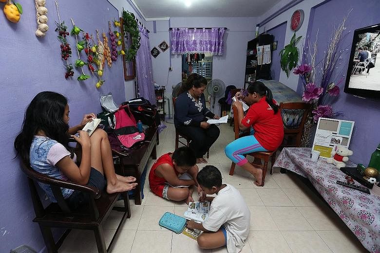 Madam Nor and her children in the living room of their two-room rental unit in Ang Mo Kio. She hopes to get her own flat again with the help of the Fresh Start Housing Scheme.