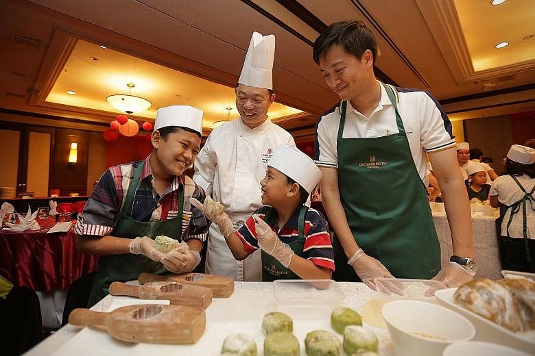 Muhammad Izzat Mohd Ismail (left) and Zulqarnain Mohd Zainuddin, both nine, having a fun time learning to make snowskin mooncakes. They were among 20 kids from the Singapore Children's Society being treated by Hong Leong Foundation to a mooncake-maki