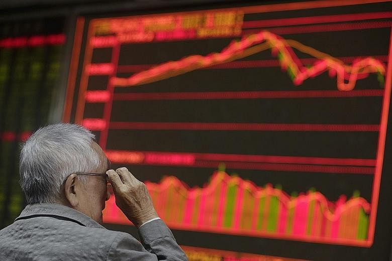 An investor monitoring stock data on an electronic board at a securities brokerage house in Beijing yesterday. China reduced interest rates and the required reserve ratio yesterday in a move that analysts believe may help to halt the downtrend in the