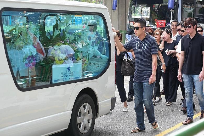 Mr Ng Su Teck (left), with his arm still bearing burn scars, behind the hearse carrying his wife's coffin. The cortege was leaving New Upper Changi Road yesterday morning.
