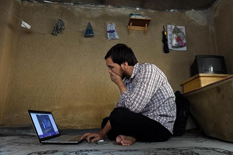 Mr Abdullah Karim Aminy looking at a photograph of his cousin on a laptop in Kabul. His cousin is one of a growing number of young Afghans who have left home to fight in Syria. Mr Abdullah's cousin has been killed in battle.