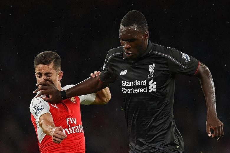 Liverpool's Christian Benteke (right) bullying his way past Arsenal defender Gabriel Paulista. The Reds are playing with intensity and purpose this season as manager Brendan Rodgers gets to mould a resolute side.