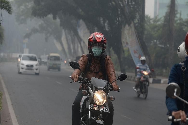 The acrid smell of burnt peat hangs heavily in the air as drivers and motorcyclists navigate the roads under challenging conditions. In South Sumatra, masks have been distributed to residents while schools have closed in Riau province.