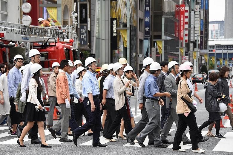 Participants making their way to a shelter during an annual disaster drill in the Ginza shopping and business district in Tokyo yesterday. Some 5,000 people working and living in the Chuo district took part in the exercise, which trains people on wha