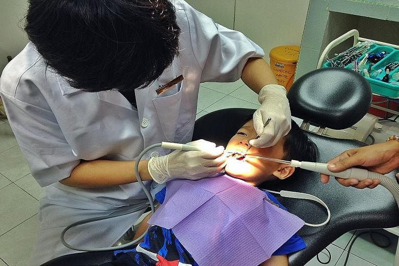 Leroy Teo, five, getting his teeth cleaned at a dental clinic in Johor Baru, where his father Steven Teo pays about RM80 (S$27). Singaporeans Neo Yiwen (far left) and Adelina Chan stocking up on household items at Tesco hypermarket in KSL Mall in JB 