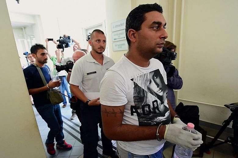 Two of the four suspects (handcuffed, each carrying a bottle of water) are led by a Hungarian police official into the Kecskemet courtroom yesterday. German Chancellor Angela Merkel has said that the migration crisis is a bigger test for the European