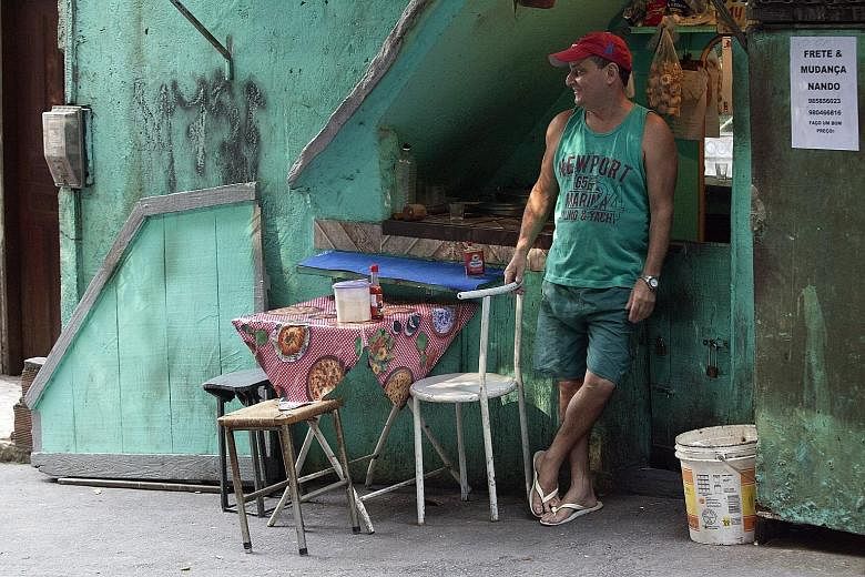 A stall-holder waits for customers at a food stand in Rio de Janeiro, Brazil. Unemployment in the country is at 7.5 per cent and rising and the national currency is down about 25 per cent this year against the US dollar.