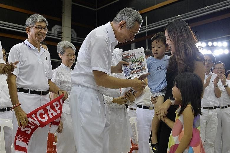 PM Lee handing a copy of the manifesto to housewife Angeline Liu, 32, and her children, three-year-old Kaleb and six-year-old Faith. With them are (from left) Communications and Information Minister Yaacob Ibrahim, Mr Lee's wife Ho Ching, Manpower Mi