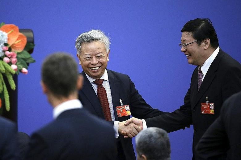 Mr Jin Liqun (centre), seen here in a file photo shaking hands with China's Finance Minister Lou Jiwei, is ready to face the challenges of his new role as president of the Asian Infrastructure Investment Bank.