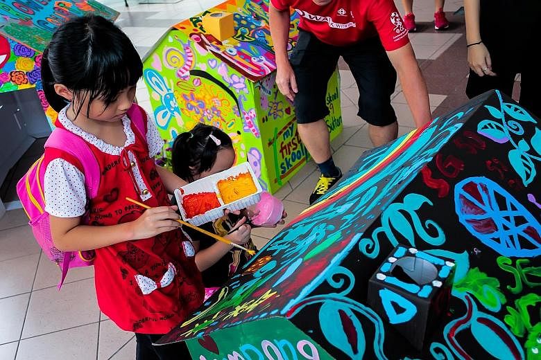 Nine-year-old Annabelle Wong painting one of the cardboard houses in the art installation at Kampong Glam Community Club.
