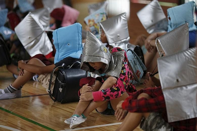 School children, wearing padded hoods to protect them from falling debris, sit in a gymnasium during an earthquake simulation exercise at an elementary school in Tokyo yesterday. The annual exercise is held nationwide, on the anniversary of the 1923 