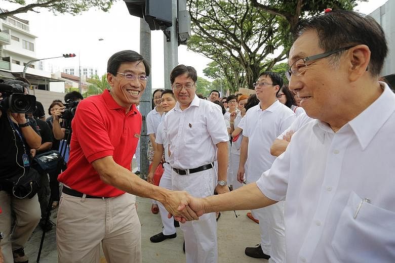 SDP chief Chee Soon Juan (left) greeting a supporter of the PAP at the nomination centre at Assumption Pathway School yesterday.