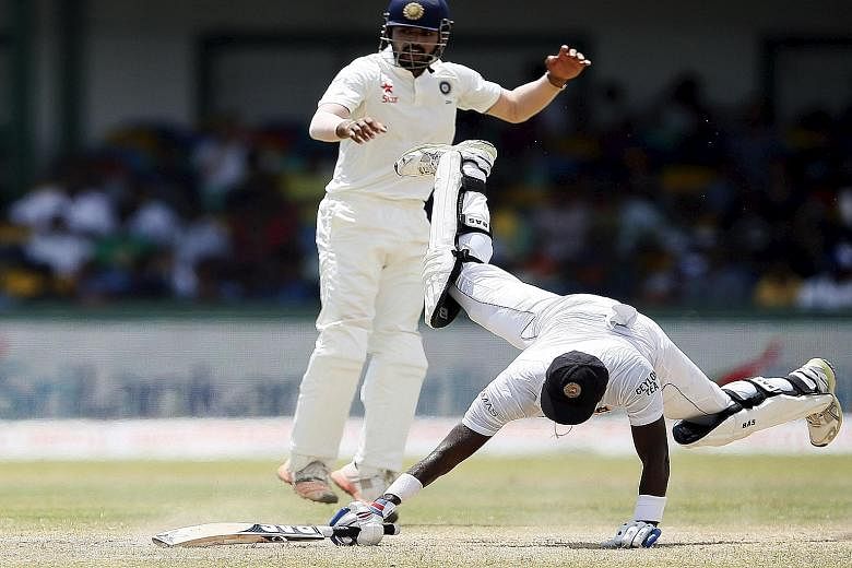 Sri Lanka's captain Angelo Mathews (right) dives back to avoid a run out as India's wicketkeeper Naman Ojha tries to catch him out during the final day of their third and final Test in Colombo. His eventual score of 110 represents his seventh Test ce