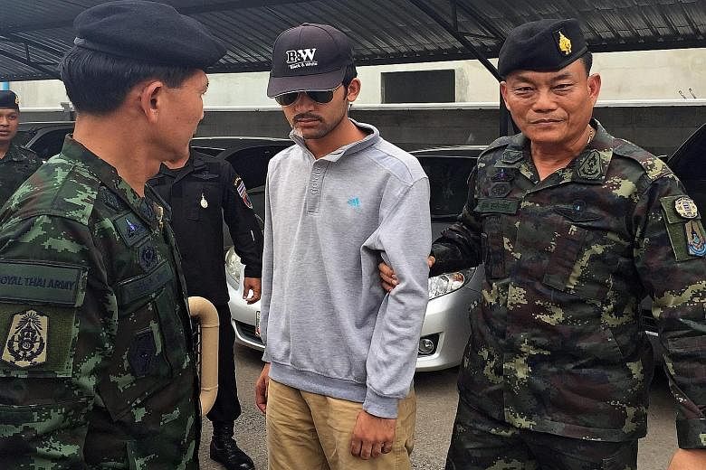 Thai soldiers escorting the Erawan Shrine bombing suspect (centre) after they arrested him near the Thai-Cambodian border yesterday. Thai police say he resembles the man caught on CCTV footage (above) planting the bomb on Aug 17.