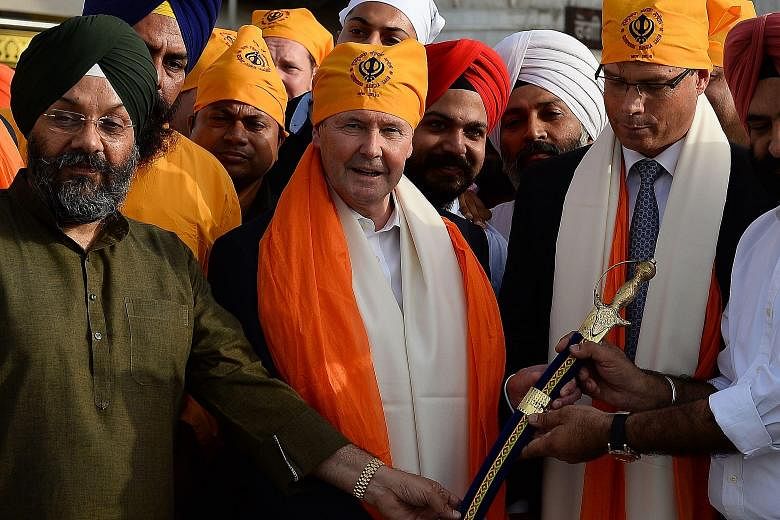 Australian Defence Minister Kevin Andrews (centre) being presented a sword at the Bangla Sahib Gurudwara, or Sikh temple, in New Delhi on Tuesday.