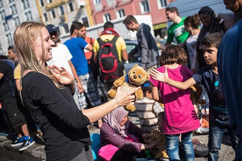 An employee of the Refugee Help Munich initiative handing out soft toys to refugee children at Munich's central train station on Tuesday.
