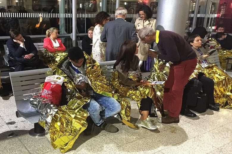 Passengers keeping warm with thermal foil blankets after their Eurostar train was stranded in Calais, France, yesterday. Five train services were suspended for hours, following reports of migrants thronging onboard.